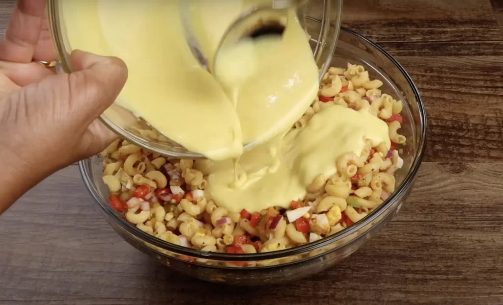 adding the dressing to the macaroni salad